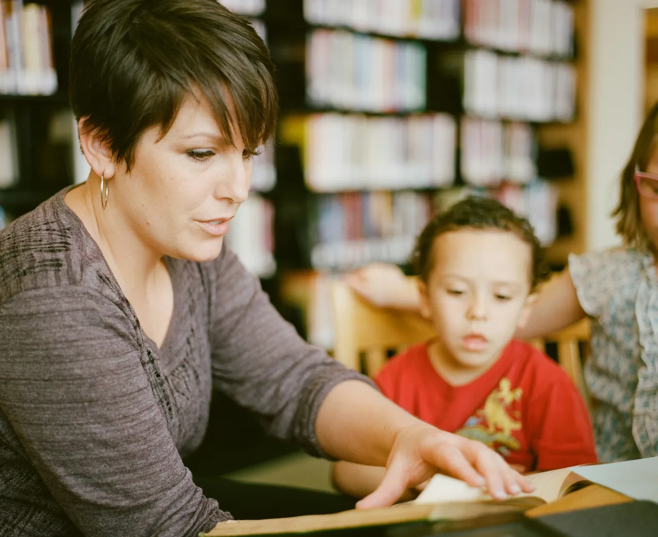 Woman holding book and child looks on