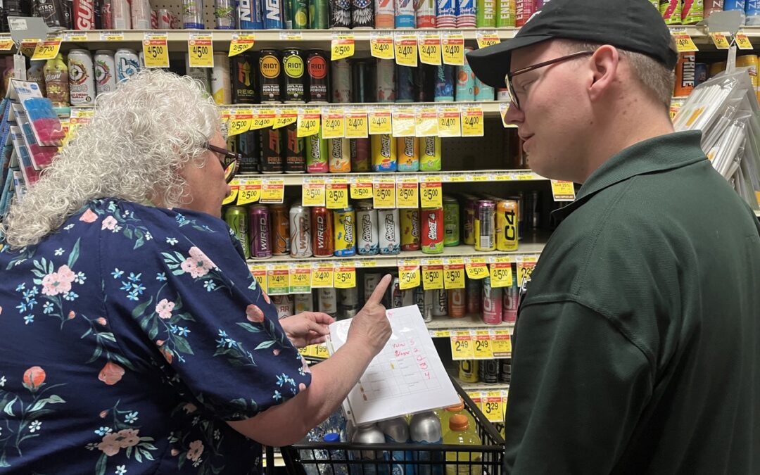 man and woman stand in a grocery aisle looking at a list