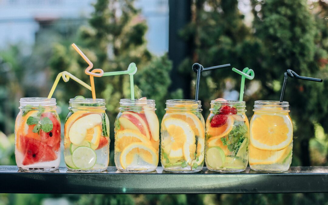 mason jars filled with fruit and water with straws